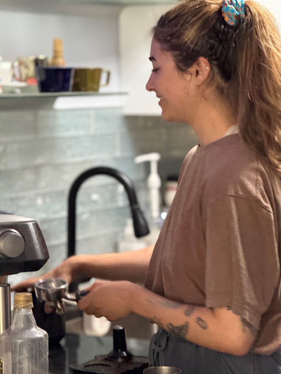 Bianca smiling while preparing coffee beside an espresso machine.