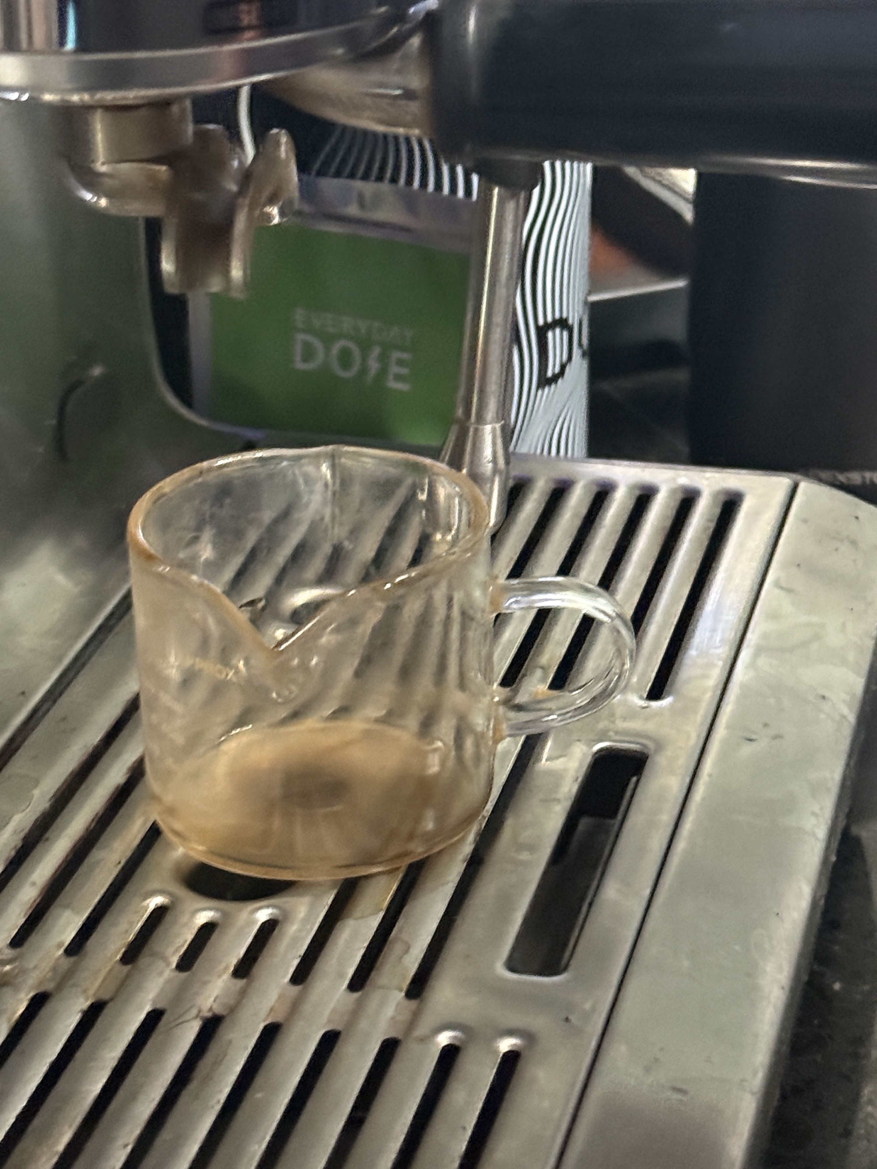 A close espresso shot being pulled into a glass cup.